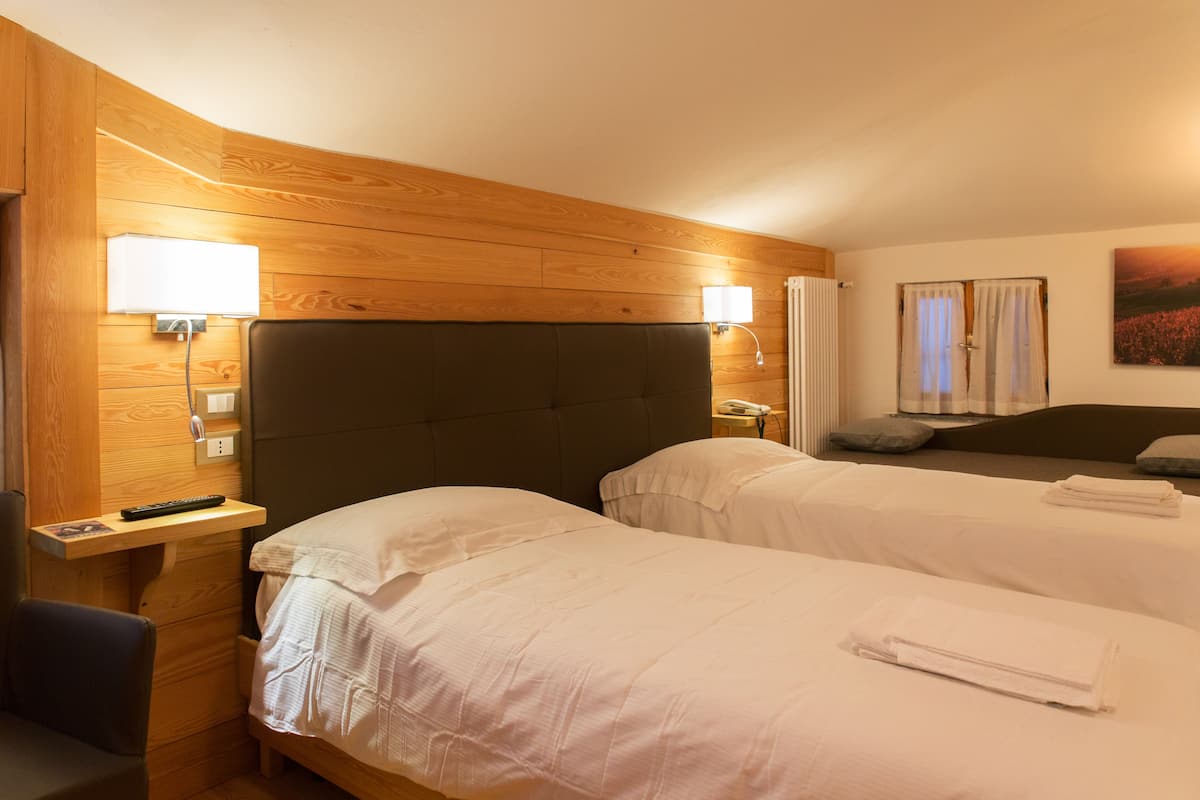 A hotel room with two beds, wooden paneling, a desk with a chair, a nightstand, and a painting on the wall.