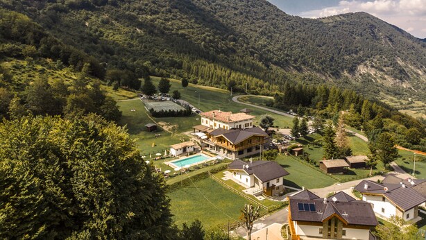 Zona residencial amb cases, piscina i un paisatge ondulat.