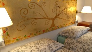 A room with a bed, two bedside lamps, and a wall with a geometric pattern and a tree design. - Bed & Breakfast La Pecora Nera (Belluno)