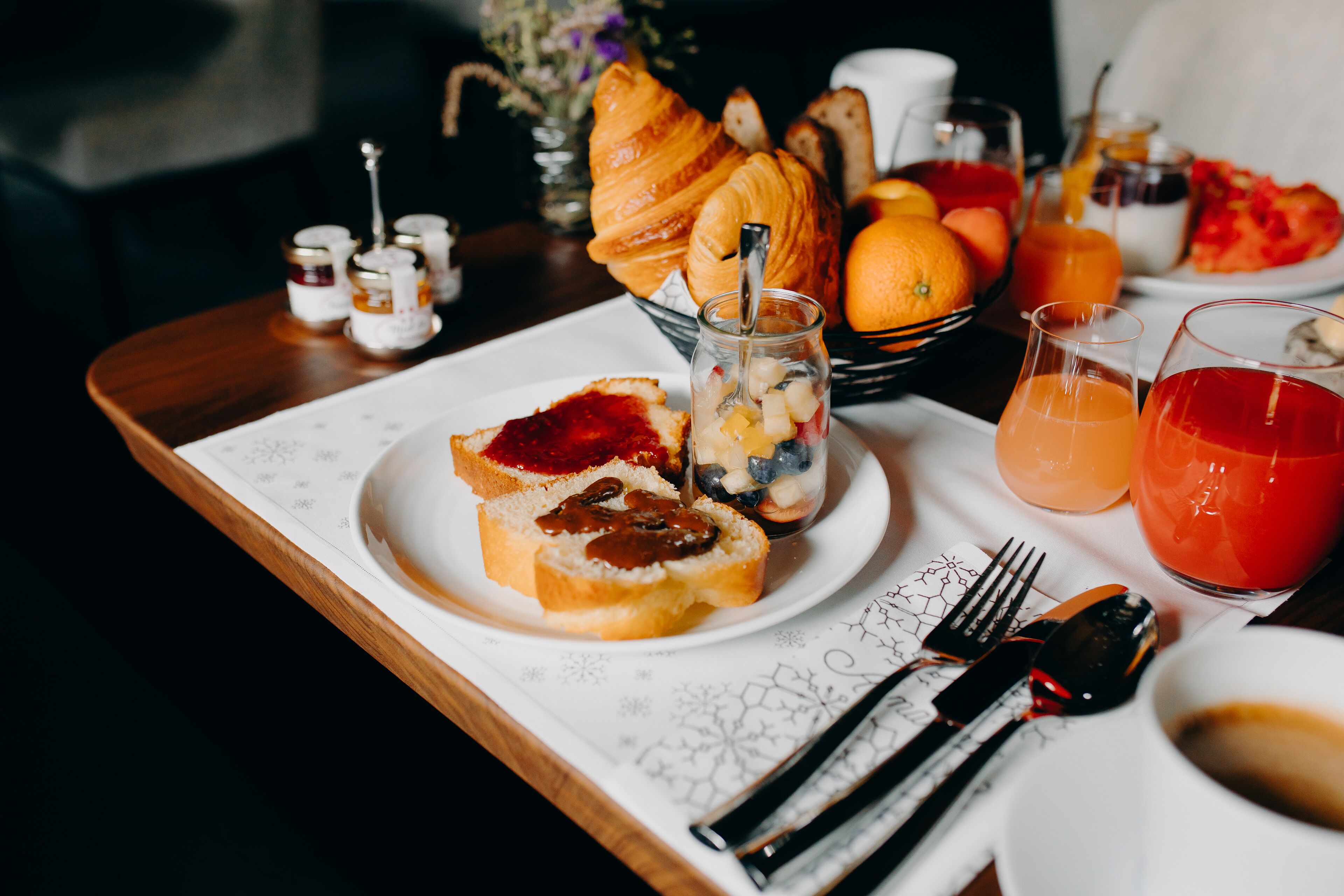 Un plateau de petit-déjeuner avec des croissants, des fruits et du jus.
