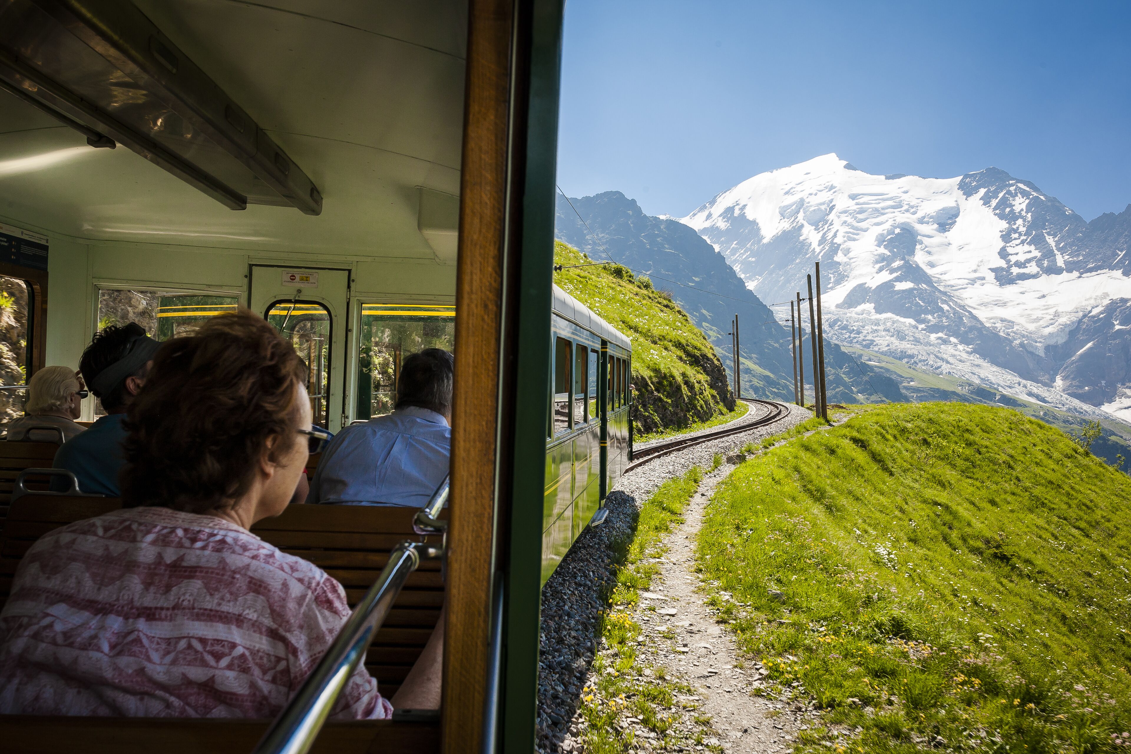 A train with passengers observing a mountainous landscape.