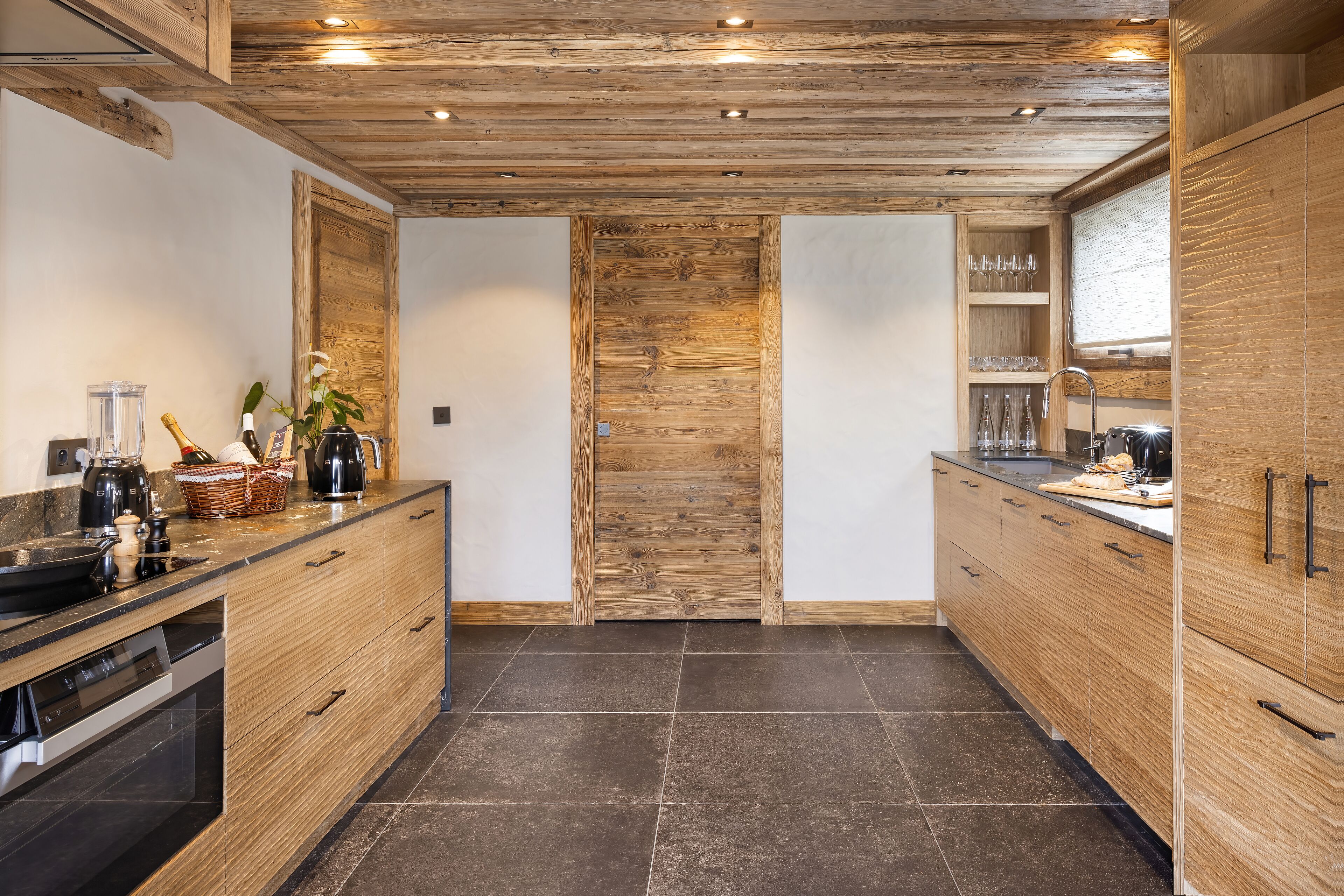 A modern kitchen with wooden cabinetry, a built-in oven, and a countertop with various appliances and a basket.