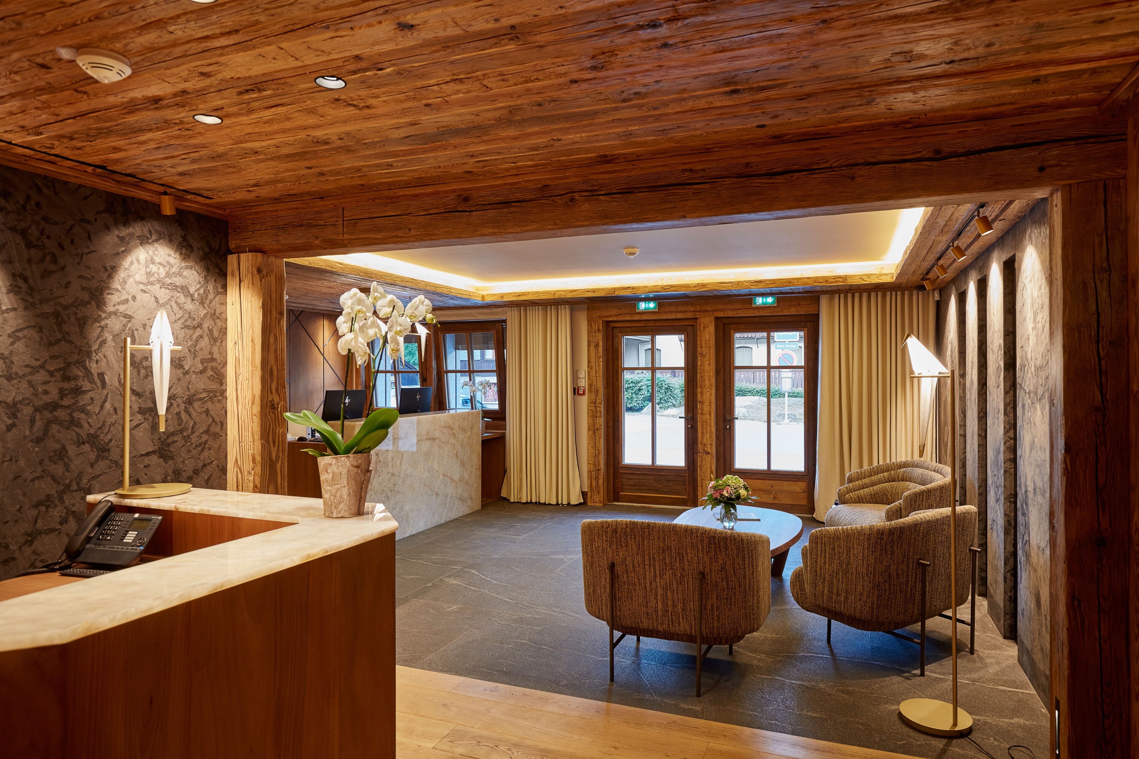 A wooden reception area with a desk, chairs, and a plant.