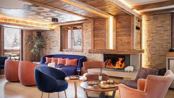 A cozy living room with a fireplace, wooden walls, and comfortable seating.