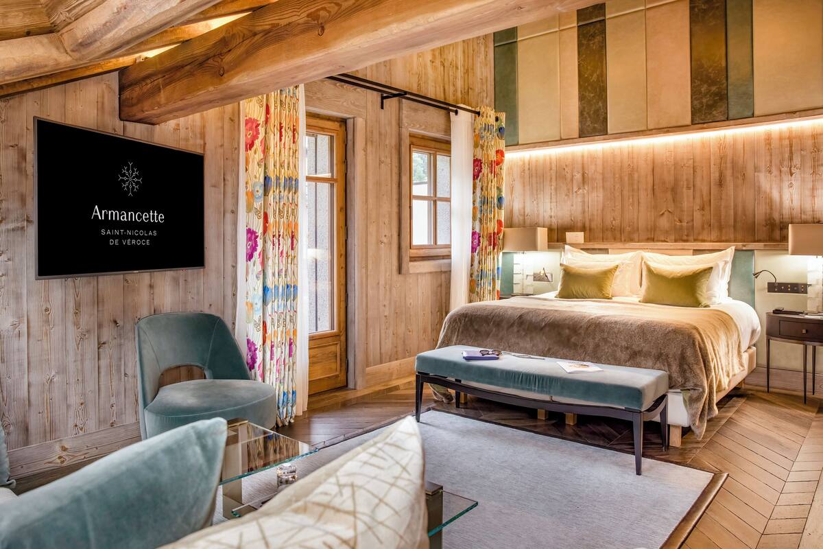 Un dormitorio moderno con cama, una silla, televisión y ventana con cortinas.