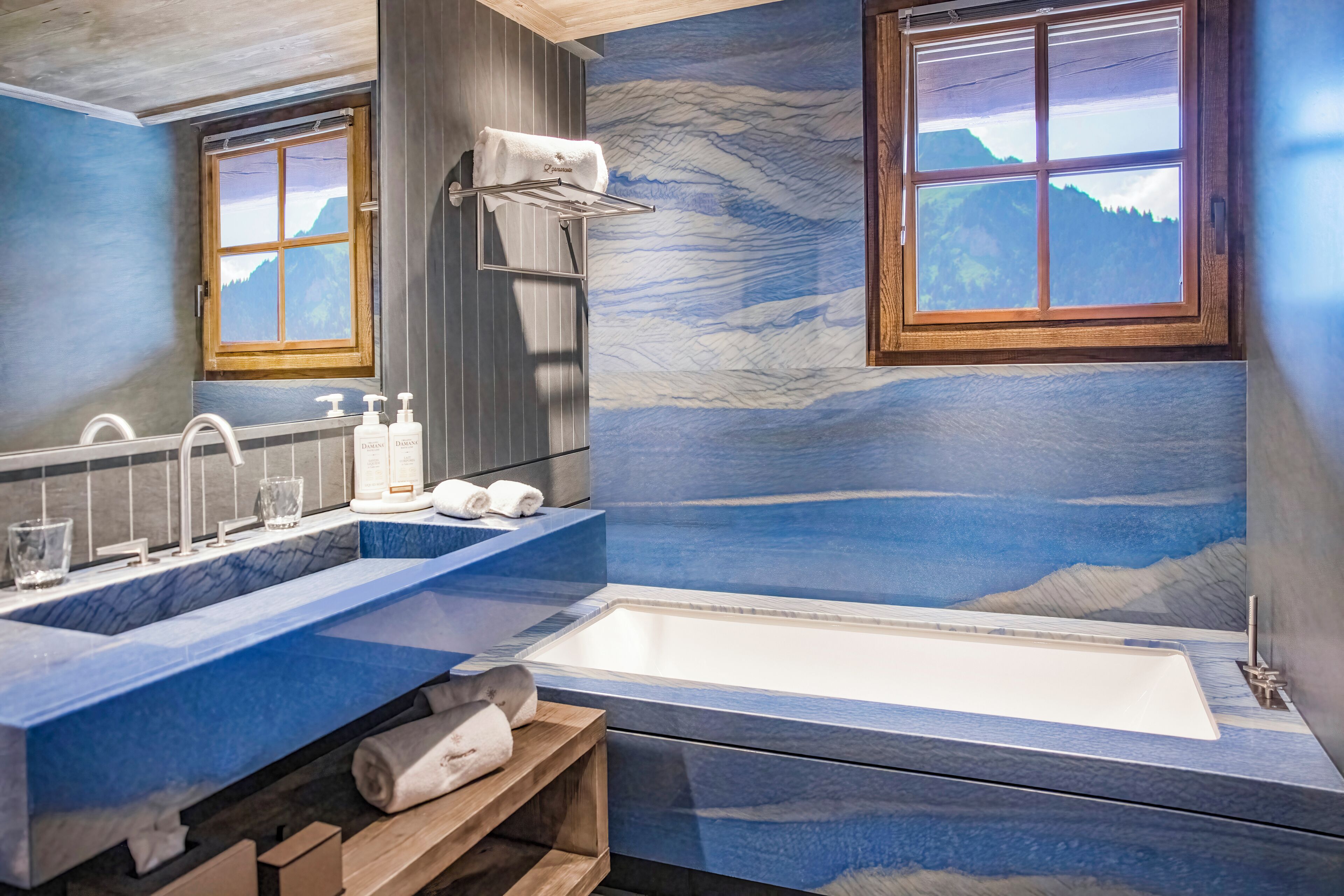 A bathroom with a marble sink, a bathtub, and a mural of a mountain landscape.