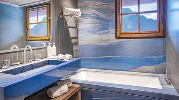 A bathroom with a marble sink, a bathtub, and a mural of a mountain landscape.