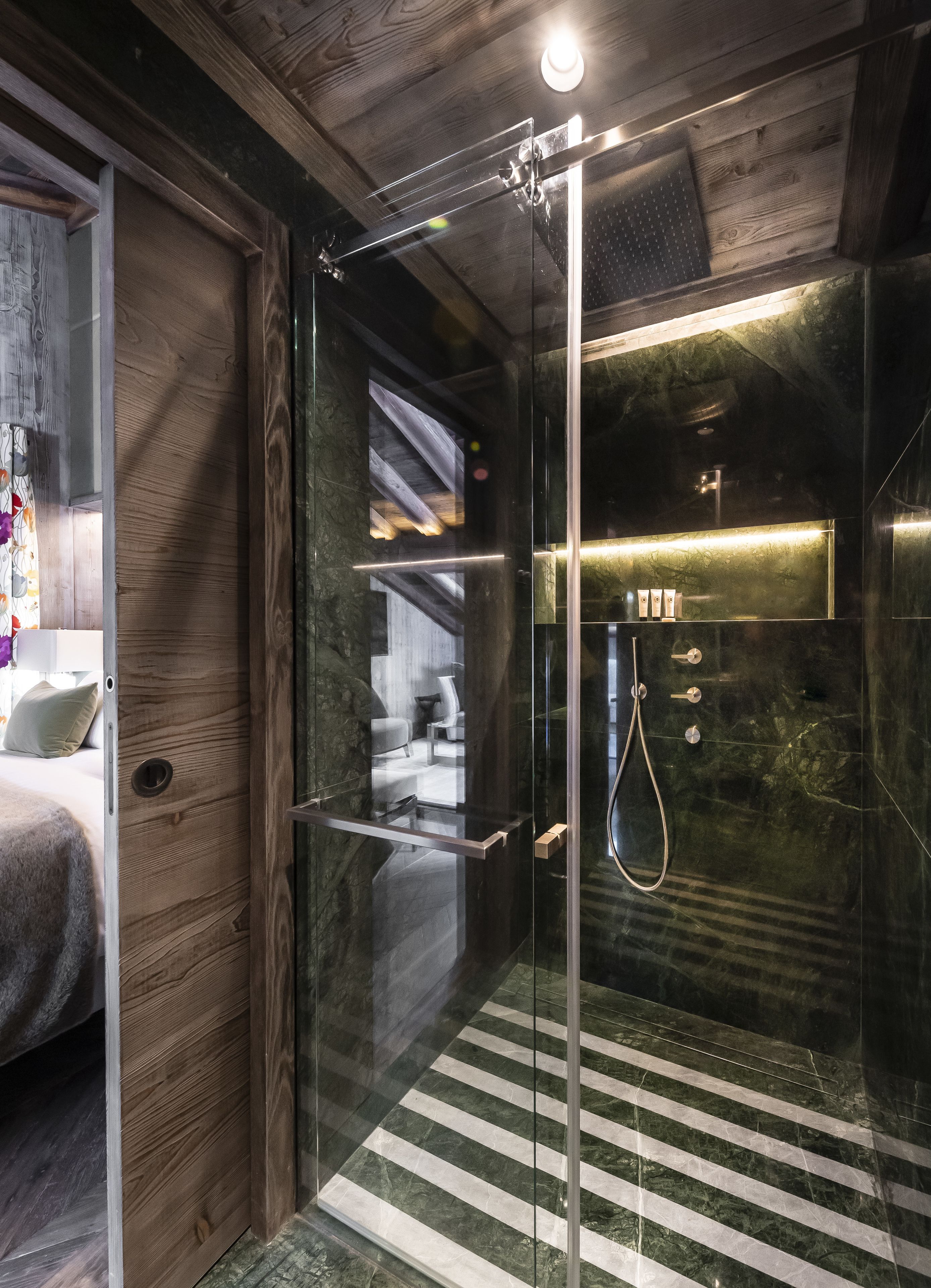 Une salle de bain moderne avec une douche à parois de verre, des murs en bois et un sol en marbre.