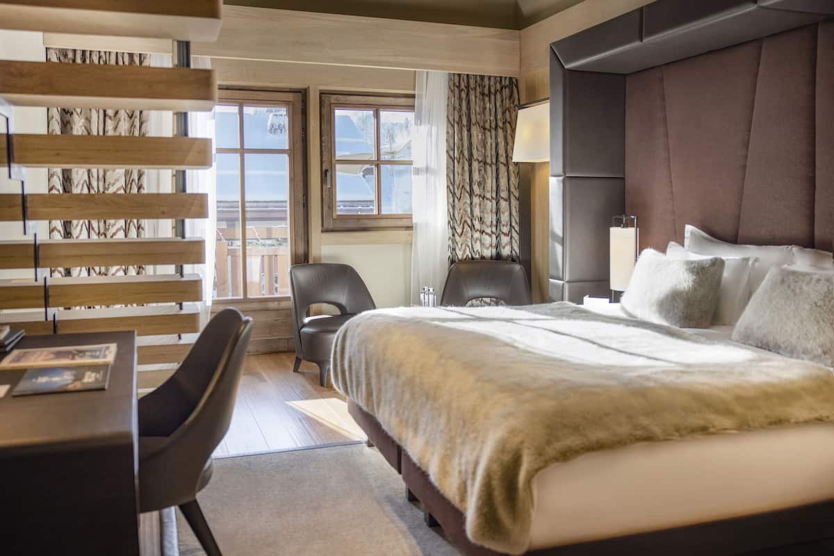 Una habitación de hotel moderna con una cama grande, un escritorio y una silla.