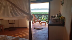 Une chambre à coucher avec un lit à baldaquin, un banc en bois et une vue sur un balcon doté d’une balustrade et d’une table.
