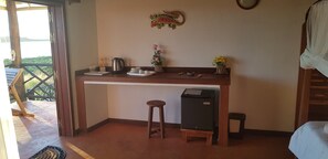 Een compacte kitchenette met een koffiezetapparaat, theeservies en een koelkast.