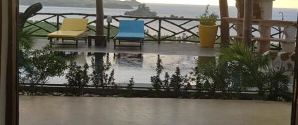 Een overdekt terras met twee loungesteilen en een plant in pot.