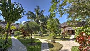 Un complexe hôtelier tropical doté de bungalows aux toits de chaume, d’un chemin principal et d’une végétation luxuriante.