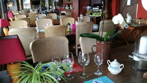 A dining area with wicker chairs, a table set with wine glasses, a teapot, and a potted plant. - Weekend Hotel Les Pieds dans l'Eau (Viviers-du-Lac)