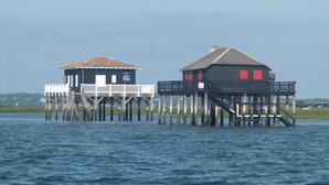 Two wooden structures on stilts over water, one with a white railing and the other with red windows. - Weekend Hotel Les Pieds dans l'Eau (Viviers-du-Lac)