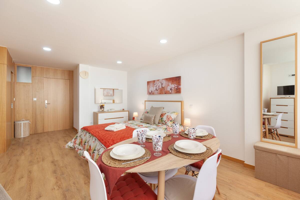 Quarto com cama, mesa de cabeceira e um espelho grande.