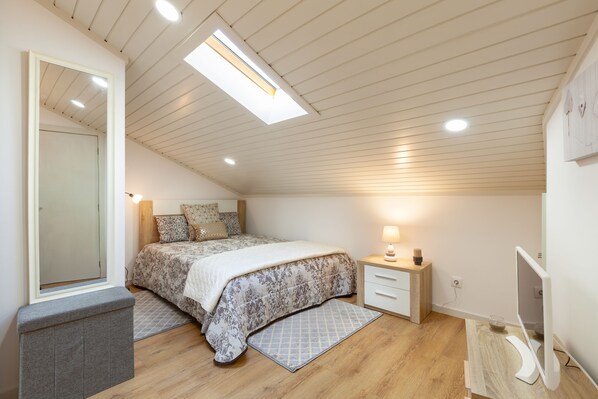 Une chambre à coucher avec un lit, une table de chevet, une lampe et un écran d’ordinateur.