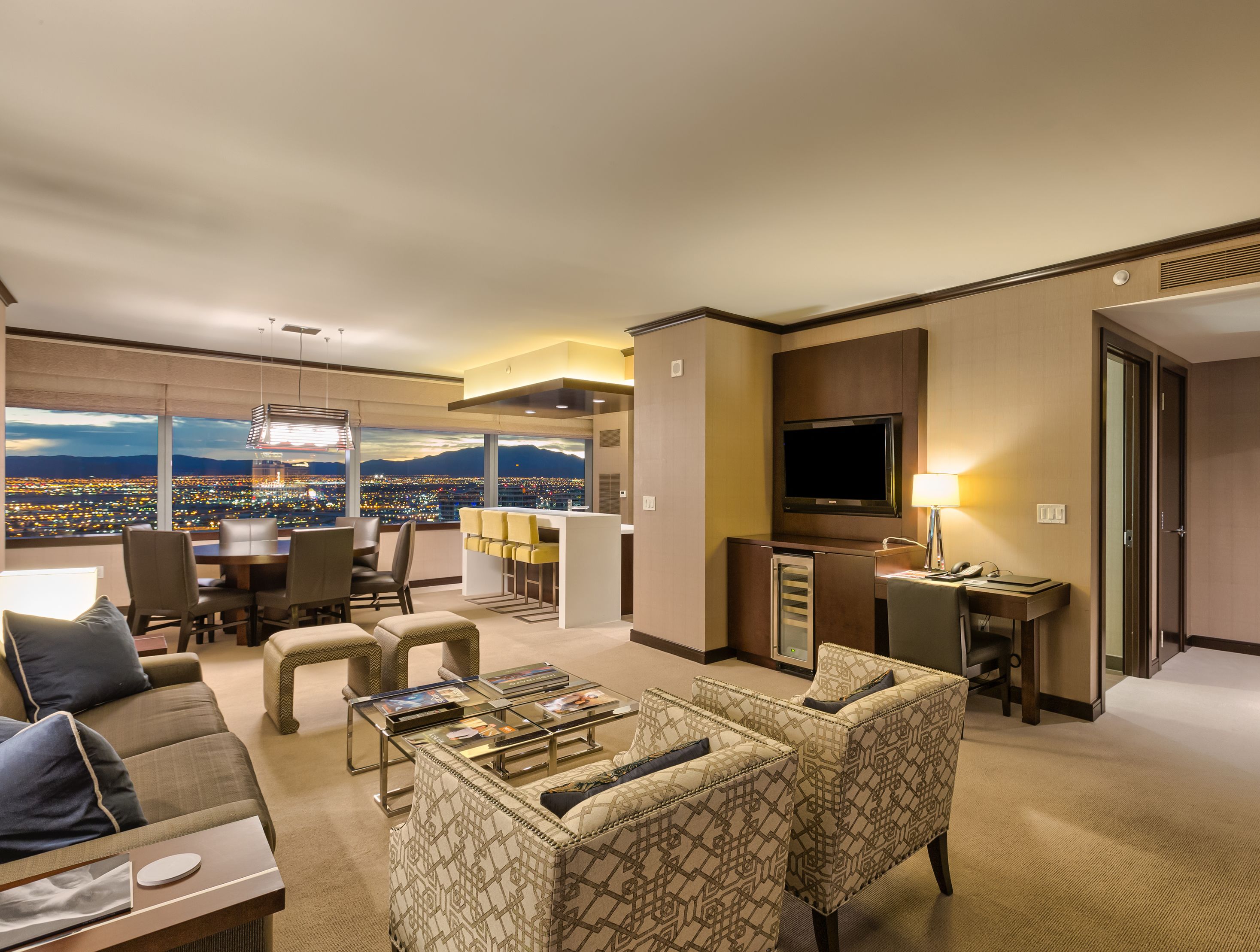 Una habitación de hotel moderna con vista a la ciudad, un área de comedor y un televisor.