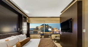 A hotel room with a large bed, a TV, a desk, and a view of the cityscape. - Secret Suites at Vdara (Las Vegas)