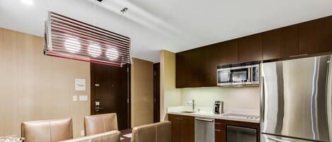 Una cocina moderna con electrodomésticos de acero inoxidable, un comedor con sillas de cuero y un ventanal corredero.