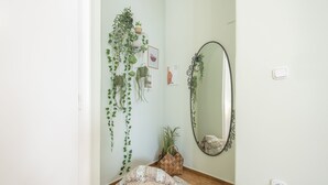 A room with a large mirror, a hanging plant, a woven basket, and a bean bag on the floor. - Boutique Acropolis Apartment  by Cloudkeys (Athens)