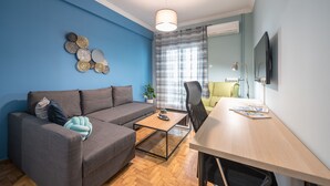 A modern living room with a grey sofa, a wooden coffee table, and a dining table with chairs. - Boutique Acropolis Apartment  by Cloudkeys (Athens)