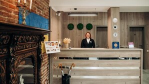 A reception desk with a wooden counter, a brick wall, and a candelabra. - Nota Bene Loft (Lviv)