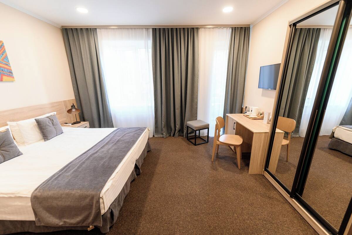 Habitación de hotel con cama, escritorio, silla y televisor.