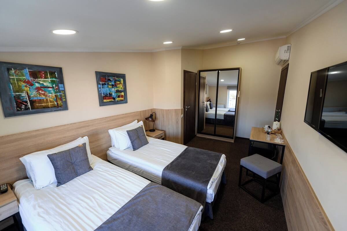 Habitación de hotel con dos camas, un escritorio, una silla y un televisor.
