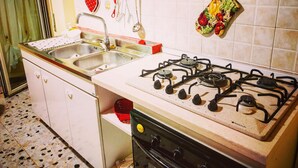 A kitchen with a gas stove, two sinks, and a variety of utensils hanging on the wall. - Central Isernia (Isernia)