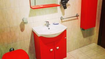 A bathroom with a red sink, toilet, and cabinet, a mirror above the sink, and a red mat on the floor.