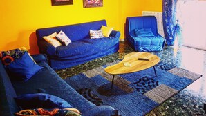 A living room with a blue sofa, a blue armchair, a wooden coffee table, and two framed pictures on the wall. - Central Isernia (Isernia)