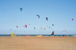 Una playa con varios cometas volando en el cielo.