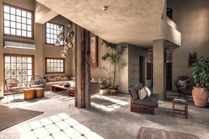 A spacious living area with large windows, a high ceiling, and a mix of seating arrangements including sofas and chairs. - Cook's Club El Gouna (El Gouna)