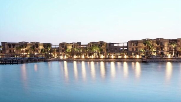 Un resort con varias construcciones, piscina y palmeras.