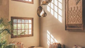 A cozy room with a large window, a hanging light fixture, and a decorative wall panel.
