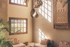 Una habitación acogedora con un amplio ventanal, una lámpara colgante y un panel decorativo en la pared.