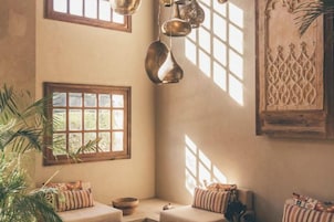 Una habitación acogedora con un amplio ventanal, una lámpara colgante y un panel decorativo en la pared.