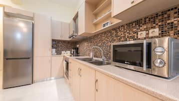 Departamento de lujo, planta baja | Cocina privada | Refrigerador, microondas, horno y parrilla de estufa