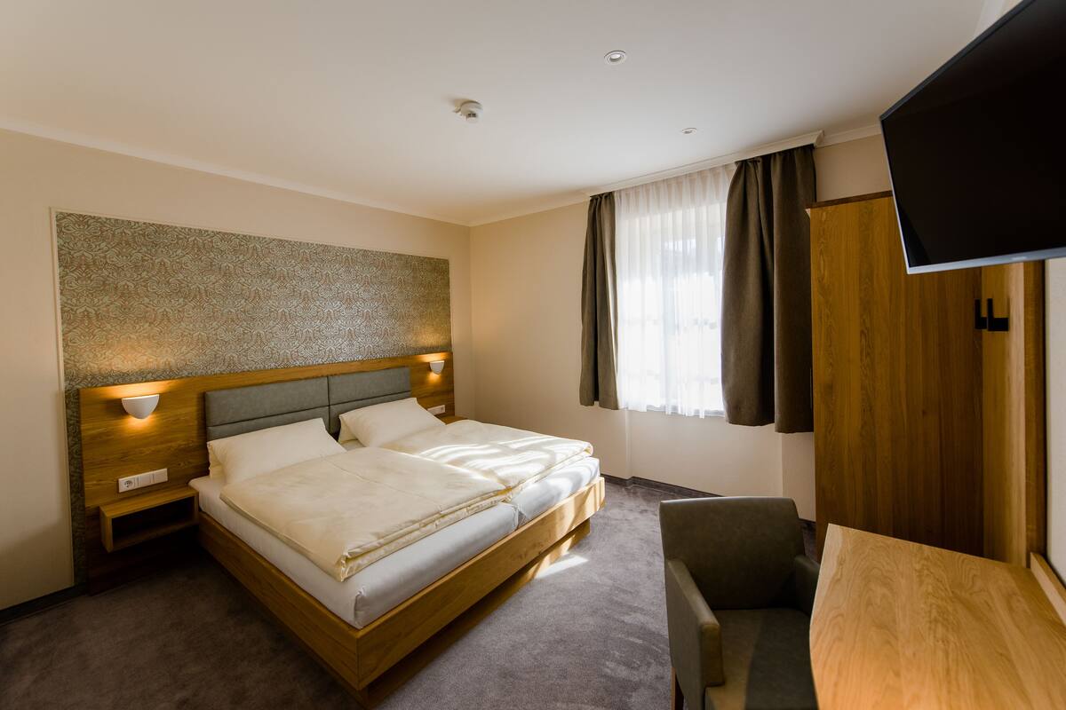 Ein Hotelzimmer mit einem hölzernen Bett, einem Flachbildfernseher, einem Schreibtisch und einem Stuhl.
