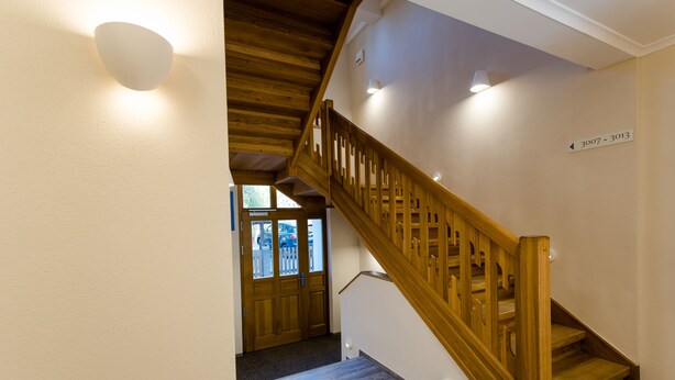A wooden staircase with a handrail, a landing with a door, and a wall sign indicating room numbers 3007-3013. - Gasthaus Sindel-Buckel Herrenhaus (Feuchtwangen)