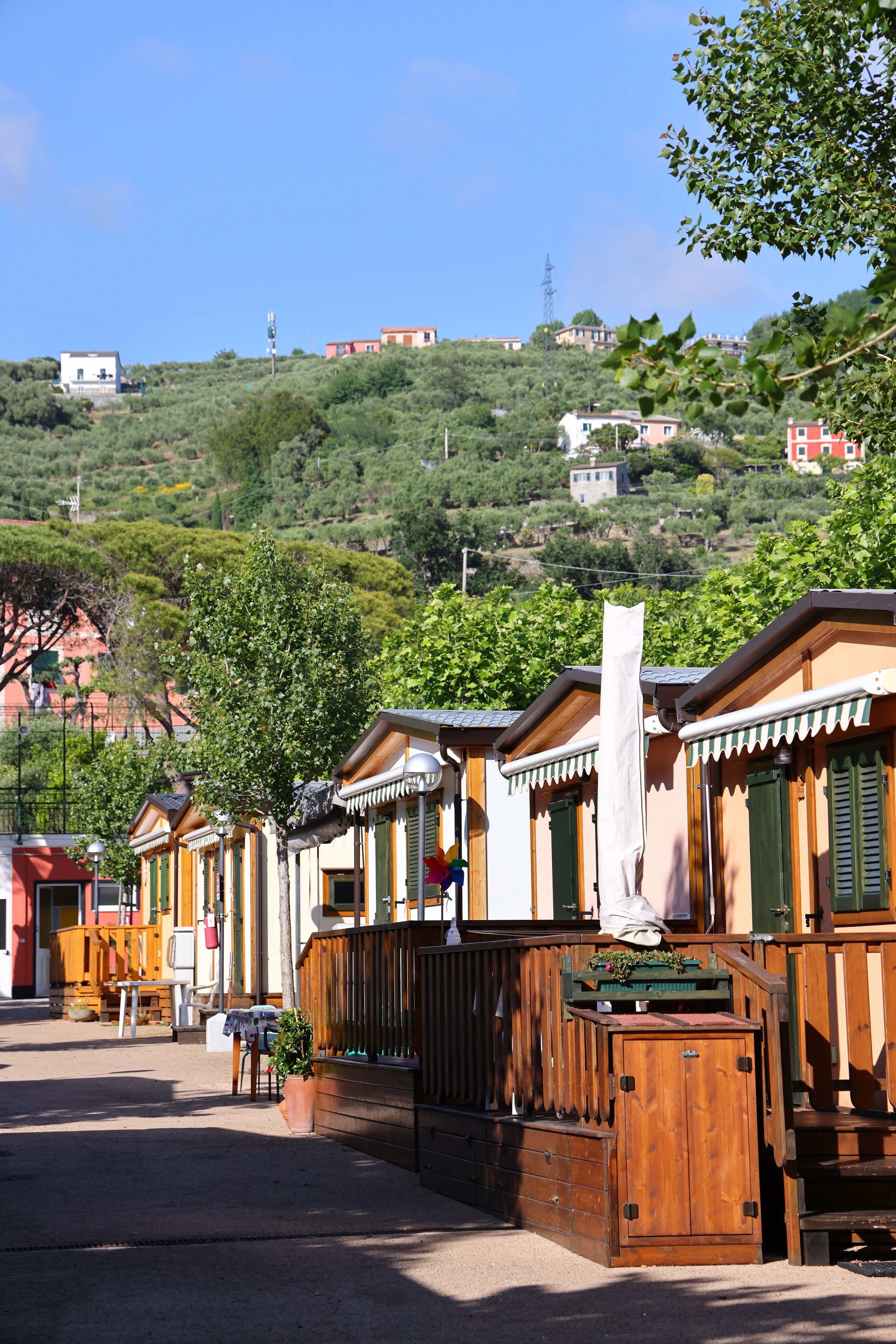 A row of wooden cabins with balconies, set against a hillside backdrop.