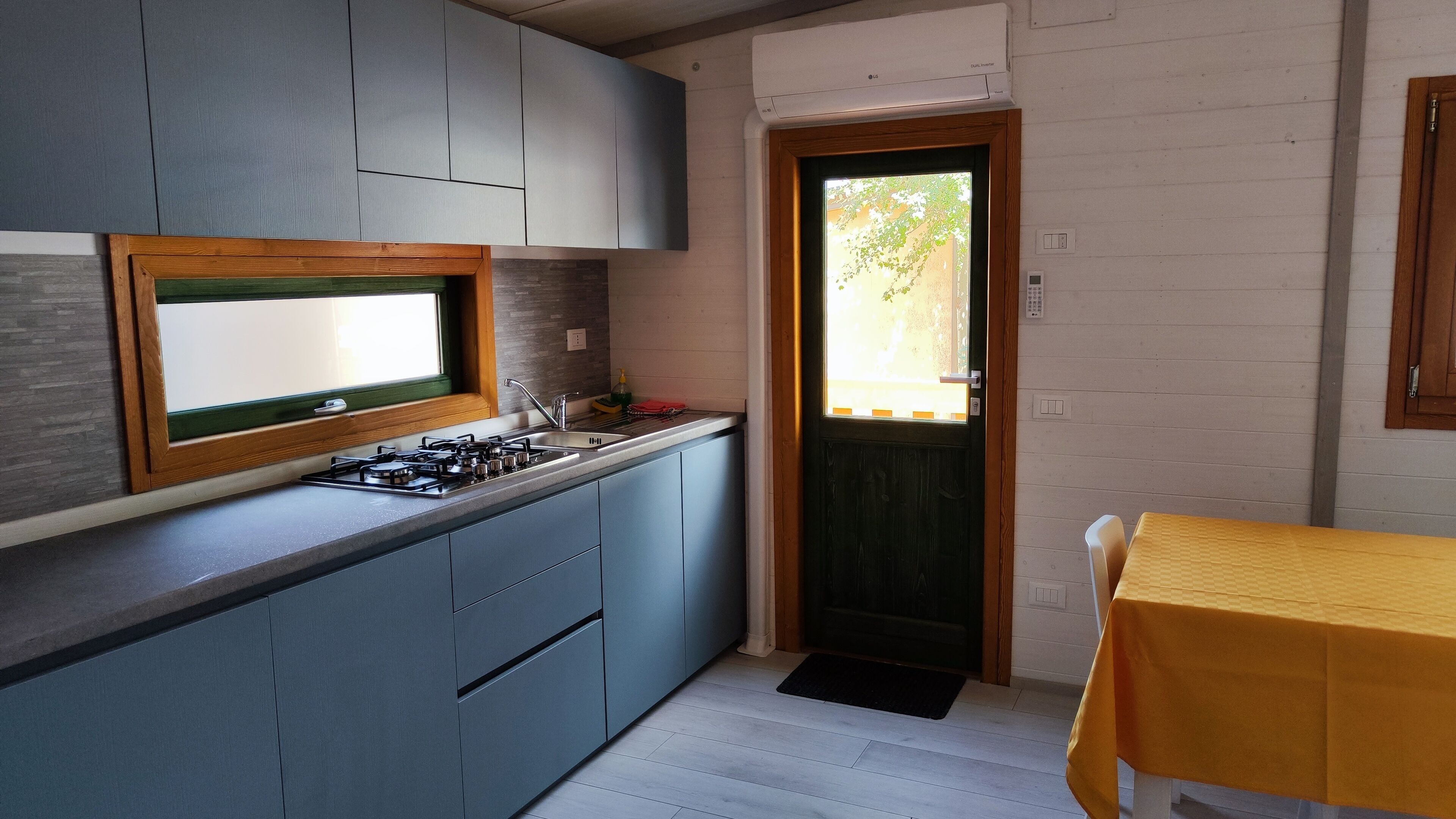 Een kleine keuken met een gasfornuis, een spoelbak en een raam met uitzicht op een tuin.