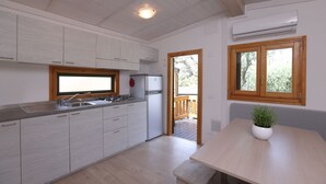 A modern kitchen with white cabinets, a stainless steel sink, and a built-in stove. There is a wooden deck visible through the door. - Parco Vacanze Lo Scoglio (Lavagna)