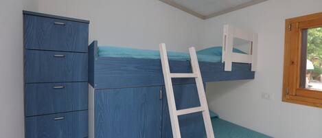 A room with a bunk bed, a wardrobe, and a window.