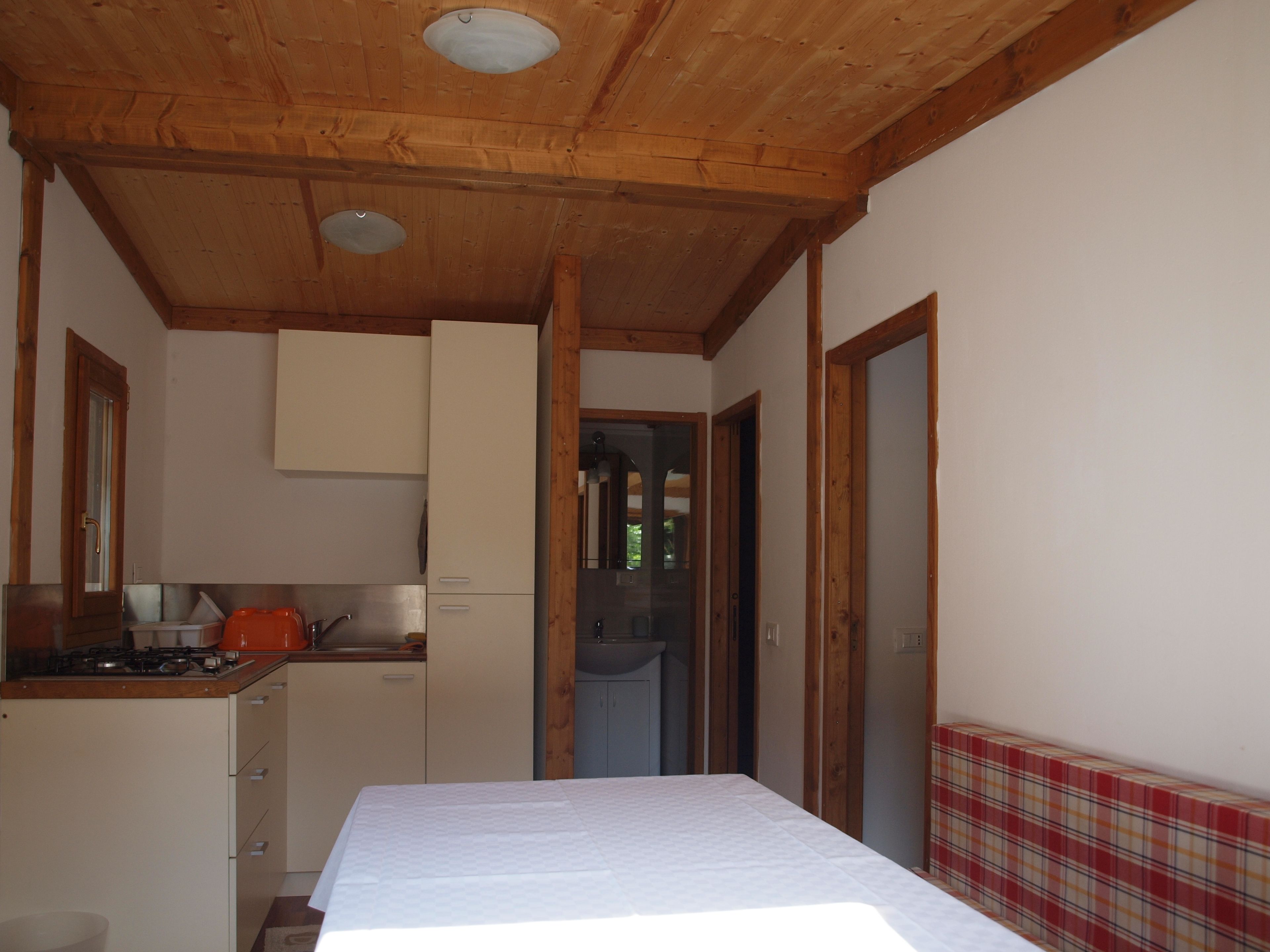 A compact kitchen with wooden beams, a stove, and cabinets.
