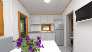 A modern kitchen with white cabinets, a built-in oven, and a refrigerator. - Parco Vacanze Lo Scoglio (Lavagna)