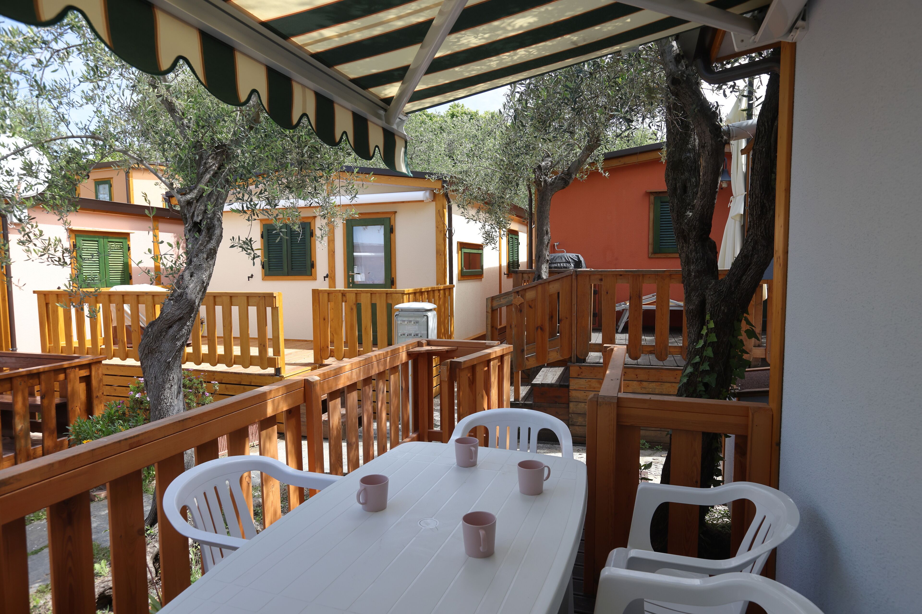 A covered outdoor seating area with wooden furniture and a table with cups.