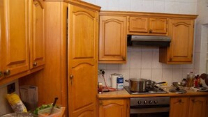 Una cocina con armarios de madera, una estufa y diversos utensilios de cocina.