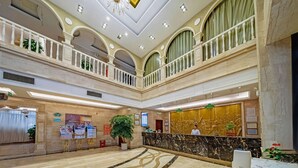 Eine Hotelhalle mit einem Marmor-Empfangstresen, einer großen Pflanze im Topf und einer Chandelier.